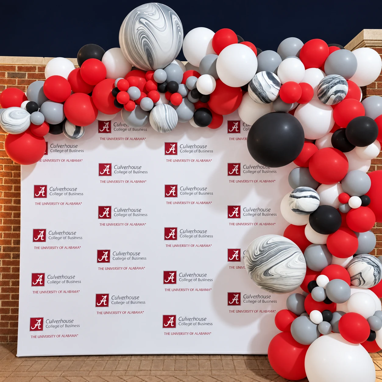 Crimson, white and black balloon garland framing a university step-and-repeat