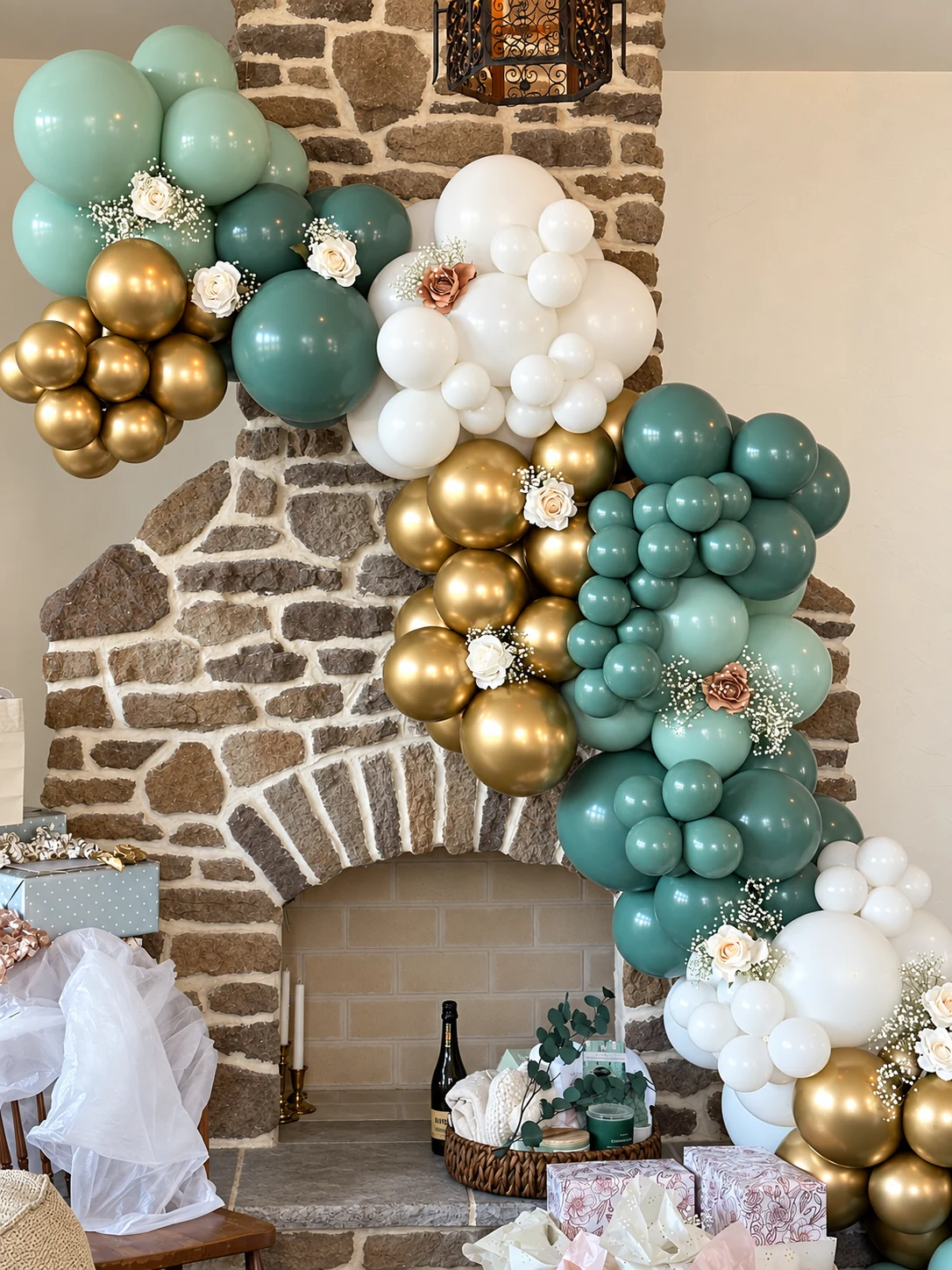 Sage, white and gold organic balloon garland around a stone fireplace
