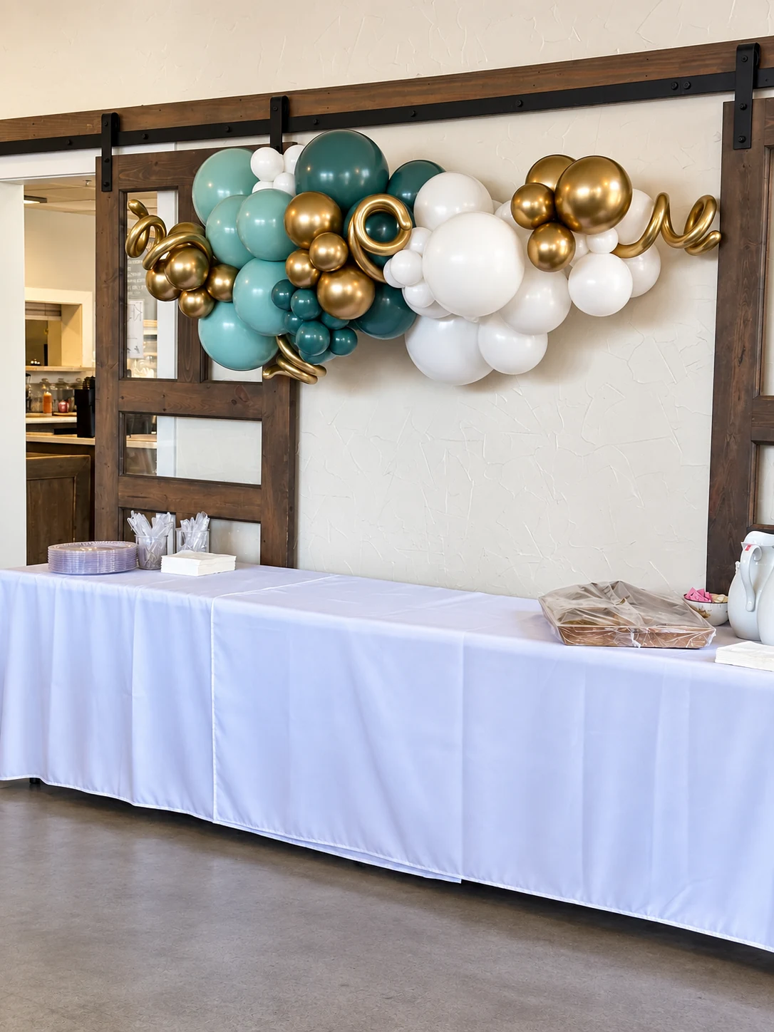 Sage, white and gold balloon garland on a greenery backdrop