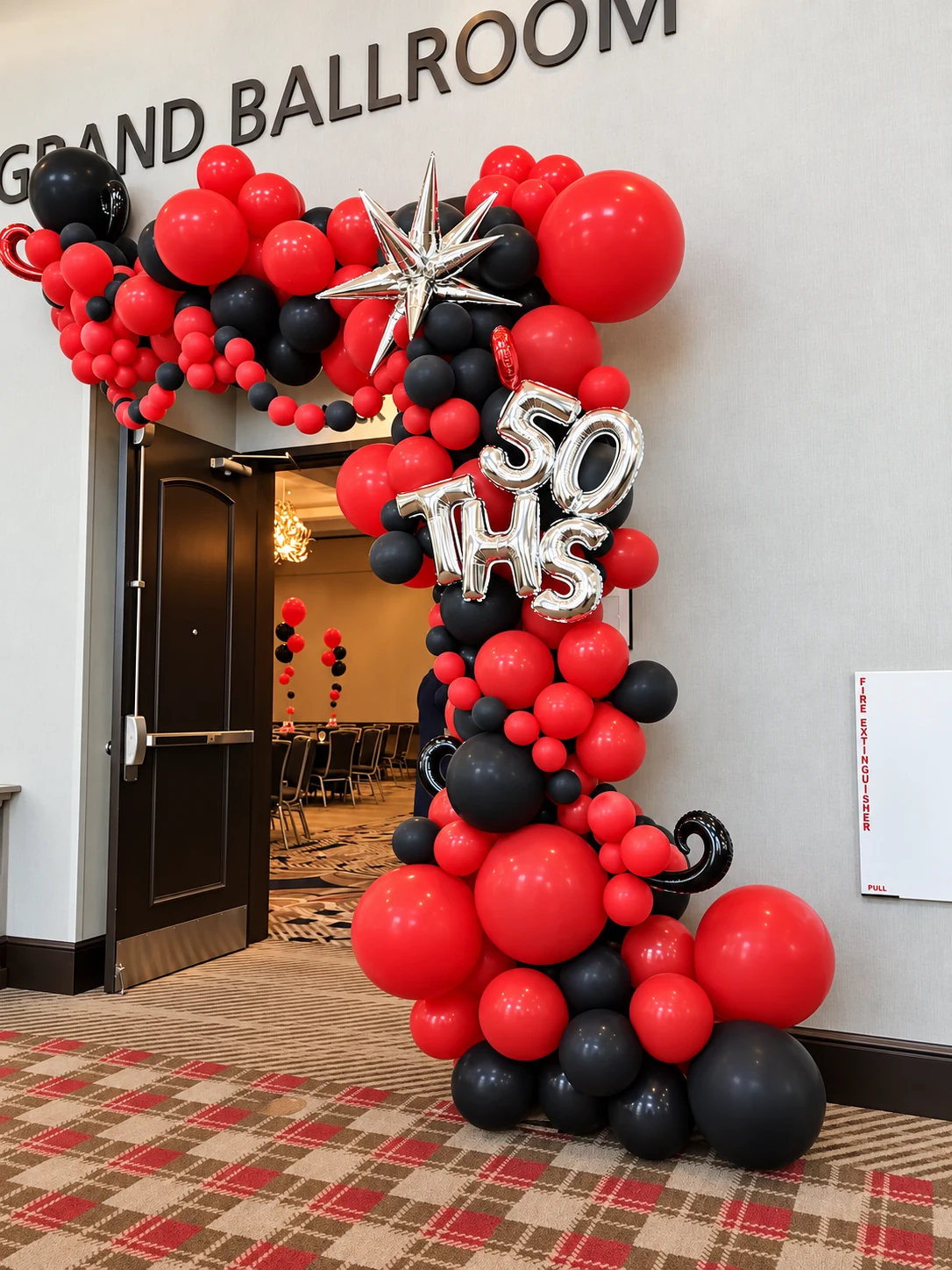 Red and black balloon garland framing a 50th birthday ballroom entrance