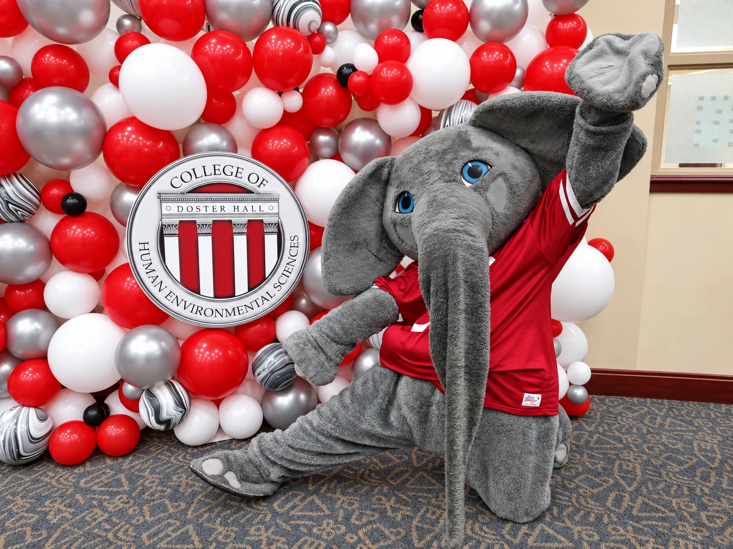 University mascot in front of a branded balloon wall