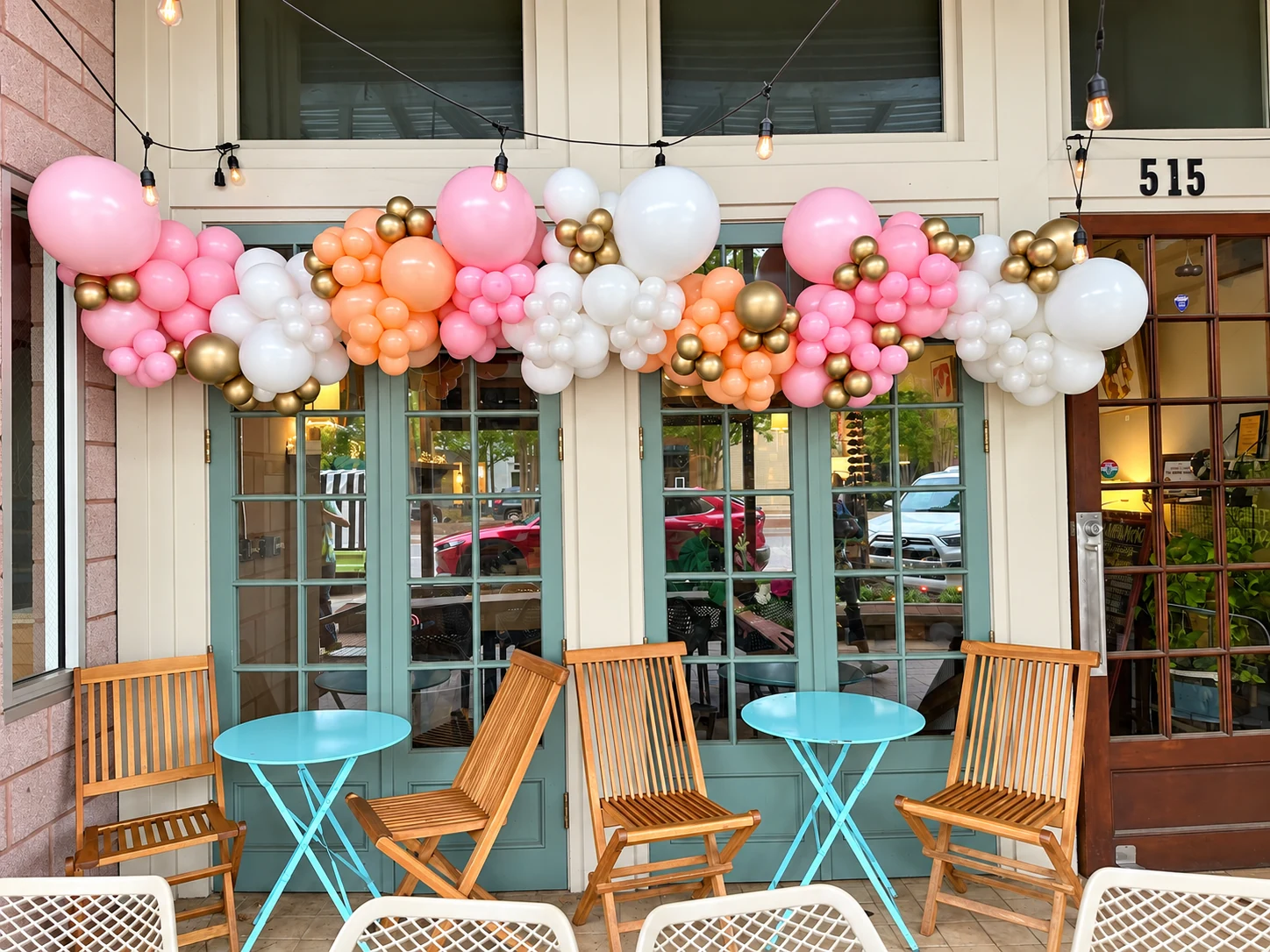 Pink, peach, white and gold balloon garland across a storefront