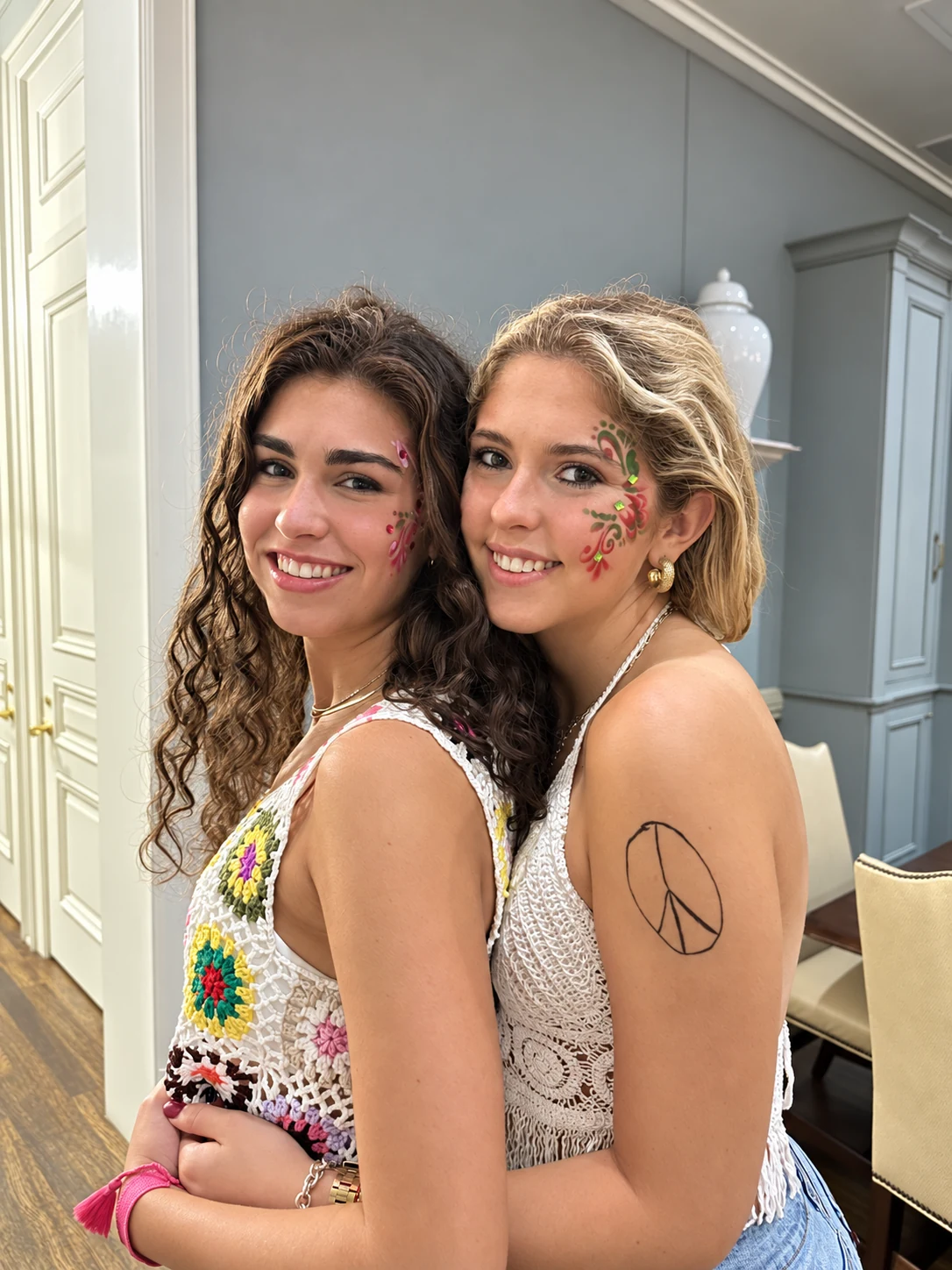 Two guests showing colorful festival face-painting designs